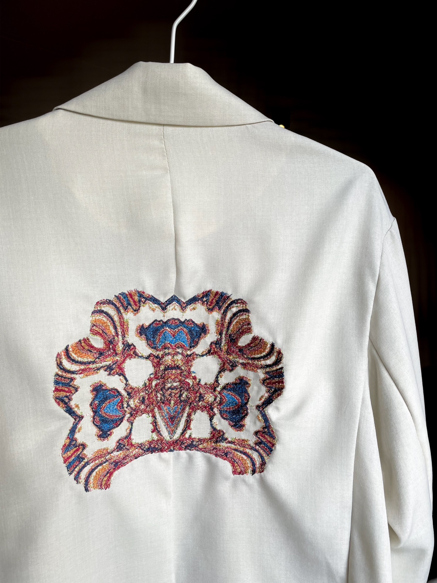 White jacket with a unique embroidered design generated by Laura's YOU tool